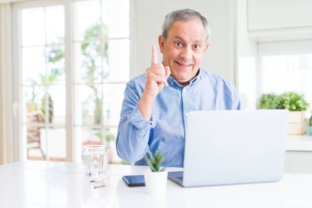 istock Handsome senior man using computer laptop working on internet surprised with an idea or question pointing finger with happy face, number one 1143484056
