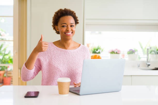 istock Young african american woman working using computer laptop doing happy thumbs up gesture with hand. Approving expression looking at the camera with showing success. 1143484922