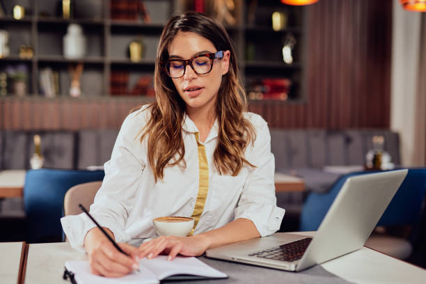 istock Businesswoman writing notes in agenda while sitting in restaurant. 1143485145