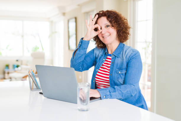 istock Senior woman working using computer laptop with happy face smiling doing ok sign with hand on eye looking through fingers 1143487193