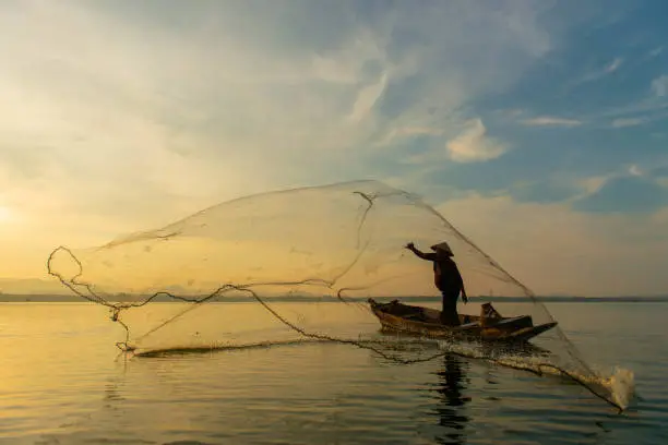 Silhouette Fisherman Fishing Nets on the boat.Thailand