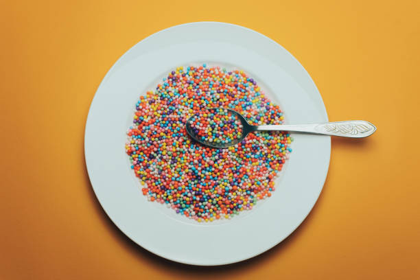 istock White plate and spoon with color preparations (vitamins, dyes, flavor enhancers, nutritional supplements, innovative technologies, candy sweets) on an orange background. 1143490837