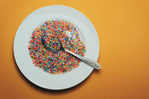 istock White plate and spoon with color preparations (vitamins, dyes, flavor enhancers, nutritional supplements, innovative technologies, candy sweets) on an orange background. 1143491540