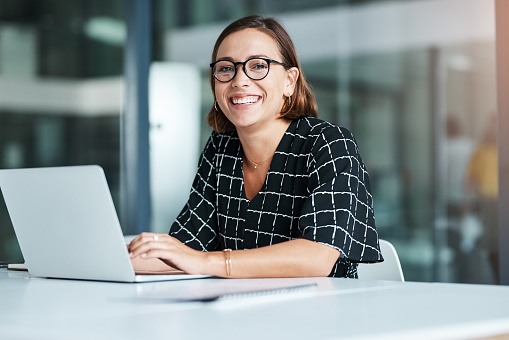 Cropped portrait of a happy young businesswoman working on a laptop in an office
