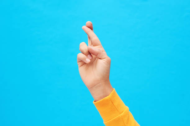 Woman hands crossing fingers on a white isolated background
