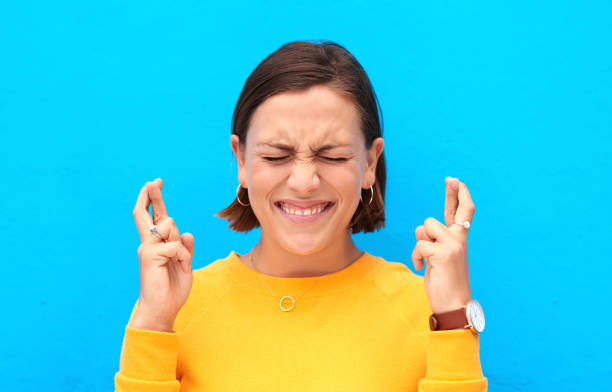 I hope the luck is on my side for this Cropped shot of a young woman crossing fingers against a blue background fingers crossed stock pictures, royalty-free photos & images