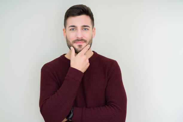 istock Young handsome man wearing a sweater over isolated background looking confident at the camera with smile with crossed arms and hand raised on chin. Thinking positive. 1143491952