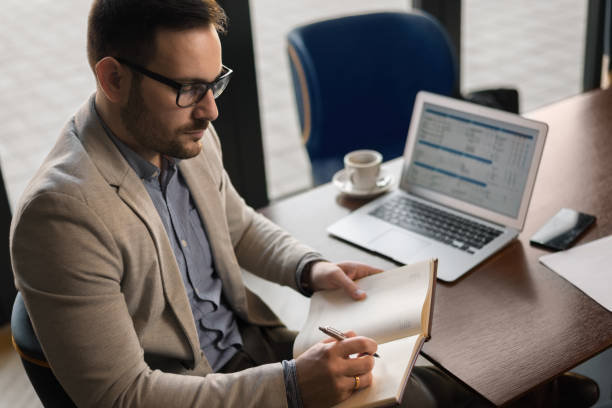 istock Profile view of a businessman taking notes while using laptop in a cafe 1143492459