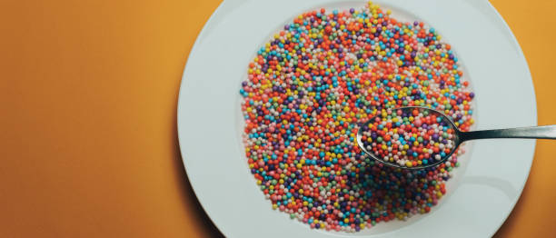 istock White plate and spoon with color preparations (vitamins, dyes, flavor enhancers, nutritional supplements, innovative technologies, candy sweets) on an orange background. 1143492857