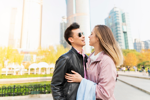 Multi -  ethnic heterosexual couple standing in the park in Shanghai embracing and enjoying together.