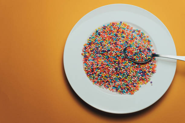 istock White plate and spoon with color preparations (vitamins, dyes, flavor enhancers, nutritional supplements, innovative technologies, candy sweets) on an orange background. 1143492886
