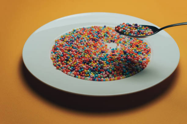 istock White plate and spoon with color preparations (vitamins, dyes, flavor enhancers, nutritional supplements, innovative technologies, candy sweets) on an orange background. 1143493470