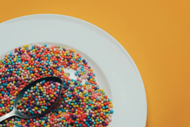 istock White plate and spoon with color preparations (vitamins, dyes, flavor enhancers, nutritional supplements, innovative technologies, candy sweets) on an orange background. 1143494037