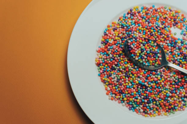 istock White plate and spoon with color preparations (vitamins, dyes, flavor enhancers, nutritional supplements, innovative technologies, candy sweets) on an orange background. 1143494126