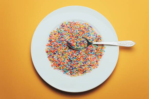 istock White plate and spoon with color preparations (vitamins, dyes, flavor enhancers, nutritional supplements, innovative technologies, candy sweets) on an orange background. 1143494354