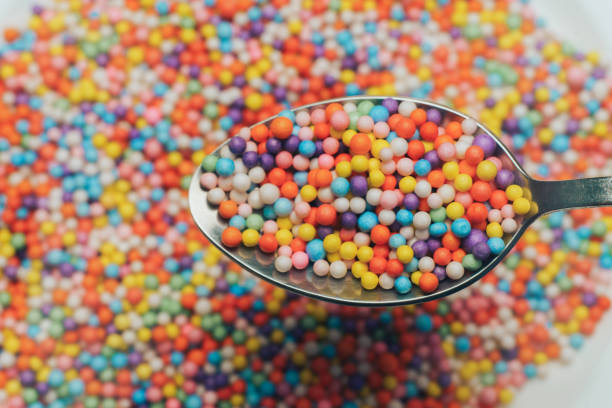 istock White plate and spoon with color preparations (vitamins, dyes, flavor enhancers, nutritional supplements, innovative technologies, candy sweets) on an orange background. Close up. 1143494366