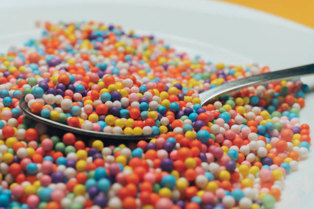 istock White plate and spoon with color preparations (vitamins, dyes, flavor enhancers, nutritional supplements, innovative technologies, candy sweets) on an orange background. Close up. 1143494398