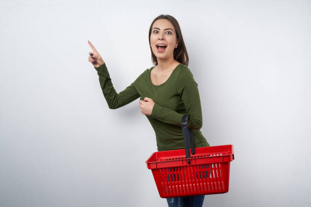 istock Surprised woman holding empty shopping basket pointing 1143494683