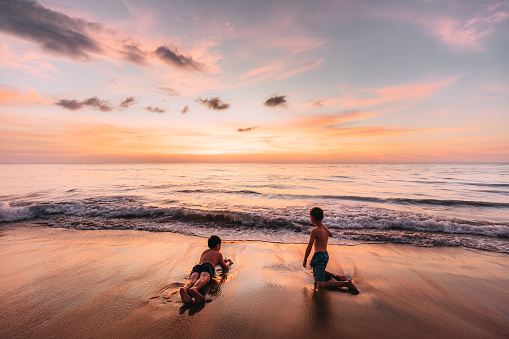boys playing in sunset at beach of Thailand