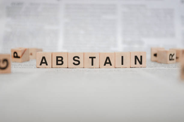 istock Abstain Word Written In Wooden Cube - Newspaper 1143495528
