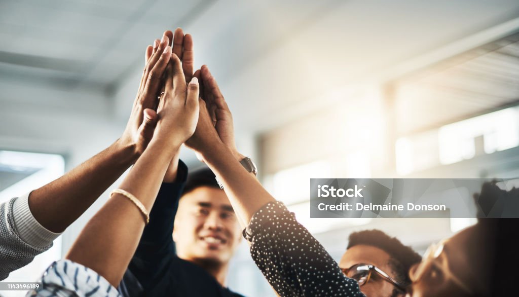 Better together Shot of a group of unrecognizable businesspeople high fiving in an office Teamwork Stock Photo