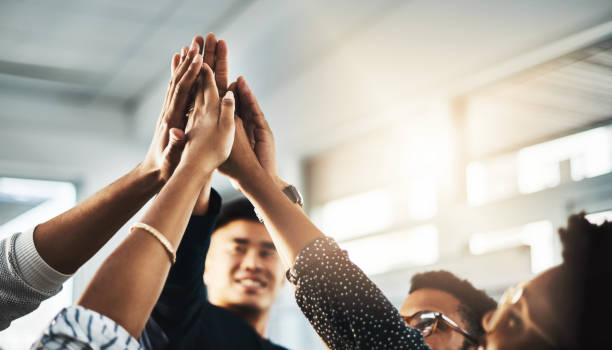 Better together Shot of a group of unrecognizable businesspeople high fiving in an office teamwork stock pictures, royalty-free photos & images