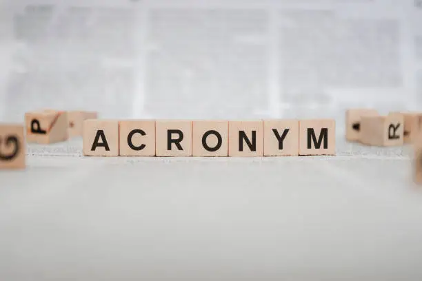 Acronym Word Written In Wooden Cube - Newspaper