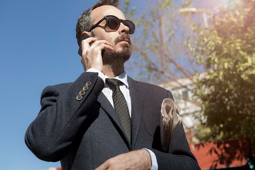 Confident businessman. Businessman on city street using smart phone