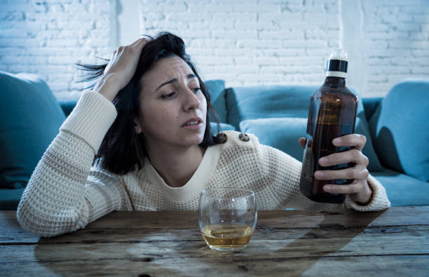 istock Drunk alcoholic depressed woman drinking scotch whiskey spirits alone at home. Feeling hopeless, week and lonely. In People lifestyle, Depression, alcohol addiction, alcoholism and drug abuse concept. 1143501448