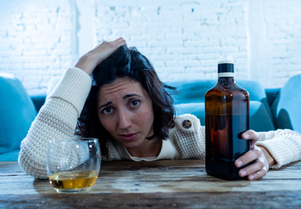 istock Drunk alcoholic depressed woman drinking scotch whiskey spirits alone at home. Feeling hopeless, week and lonely. In People lifestyle, Depression, alcohol addiction, alcoholism and drug abuse concept. 1143501980