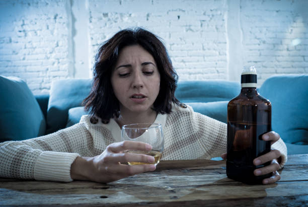 istock Drunk alcoholic depressed woman drinking scotch whiskey spirits alone at home. Feeling hopeless, week and lonely. In People lifestyle, Depression, alcohol addiction, alcoholism and drug abuse concept. 1143502041