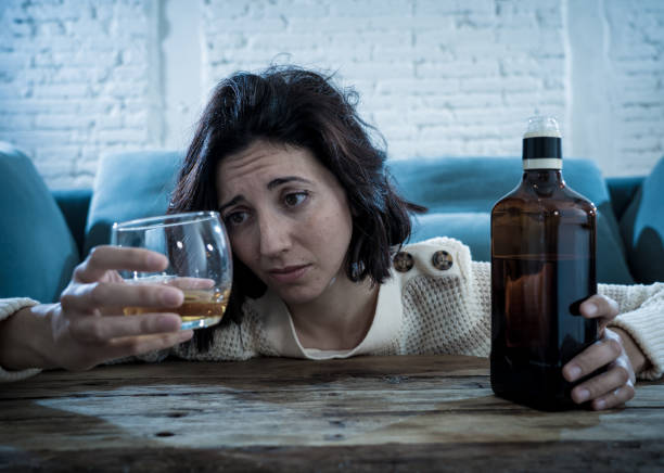 istock Drunk alcoholic depressed woman drinking scotch whiskey spirits alone at home. Feeling hopeless, week and lonely. In People lifestyle, Depression, alcohol addiction, alcoholism and drug abuse concept. 1143502043