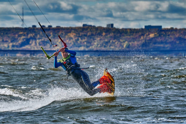 A male kiter slides on the surface of the water. Splashes of water fly apart. A male kiter slides on the surface of the water. Splashes of water fly apart. kite sailing stock pictures, royalty-free photos & images