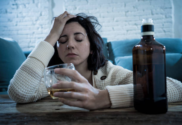 istock Drunk alcoholic depressed woman drinking scotch whiskey spirits alone at home. Feeling hopeless, week and lonely. In People lifestyle, Depression, alcohol addiction, alcoholism and drug abuse concept. 1143502544