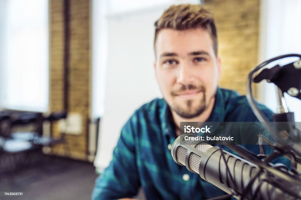 Attractive Young Man speaking Into Microphone. Man and podcast host Talking to Microphone. 30-39 Years Stock Photo