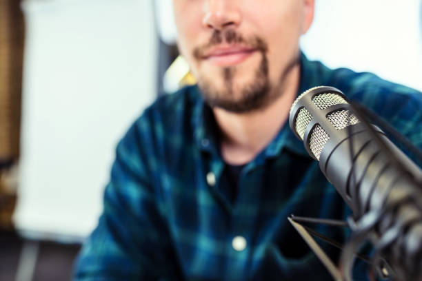 istock Young man recording a podcast smiling to camera, close up. 1143503741