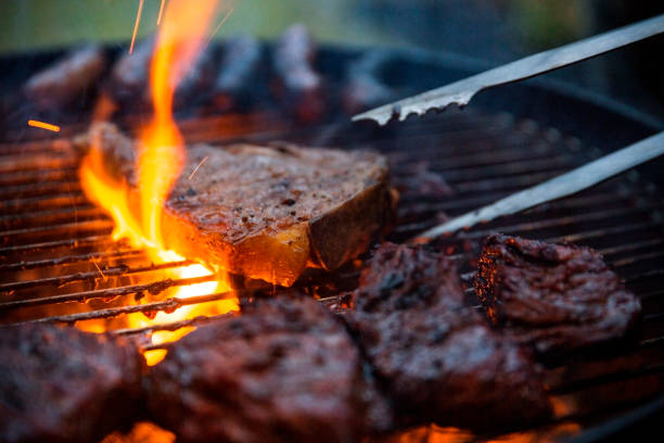 flammengegrillte steaks werden auf dem grill mit tongs gedreht - steak meat strip steak restaurant stock-fotos und bilder