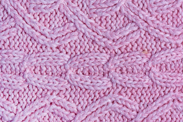 istock Knitted texture with patterns close-up. Blank pink background for layouts. Light photo. 1143505317
