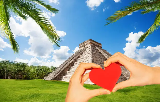 Photo of Hand hold red heart in Chichen Itza pyramid Mexico