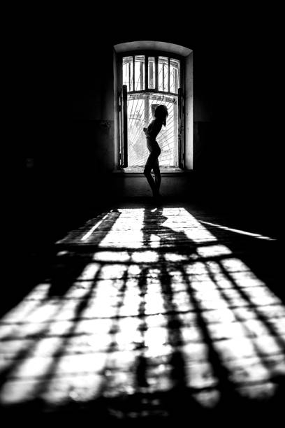 istock beautiful woman posing at the window on dark background in studio 1143509575