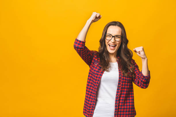 istock Winning success woman happy ecstatic celebrating being a winner. Dynamic energetic image of multiracial Caucasian Asian female model isolated on yellow background waist up. 1143509609