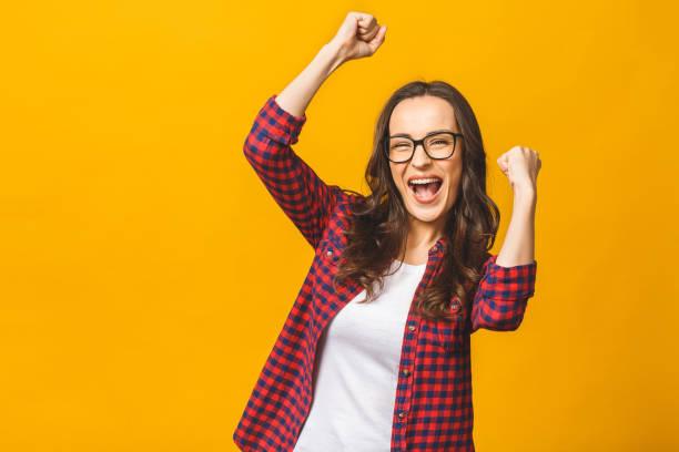 istock Winning success woman happy ecstatic celebrating being a winner. Dynamic energetic image of multiracial Caucasian Asian female model isolated on yellow background waist up. 1143509899