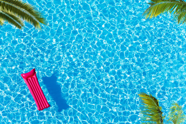 Vacation pool with matrass surface and palm trees Vacation pool hotel view from above with ping matrass floating, water surface and palm trees matrass stock pictures, royalty-free photos & images