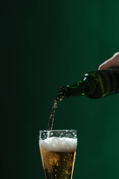 istock pouring beer into glass with foam isolated on green, st patrick day concept 1143513388