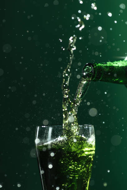 istock pouring beer into glass with splashes isolated on green, st patrick day concept 1143513455