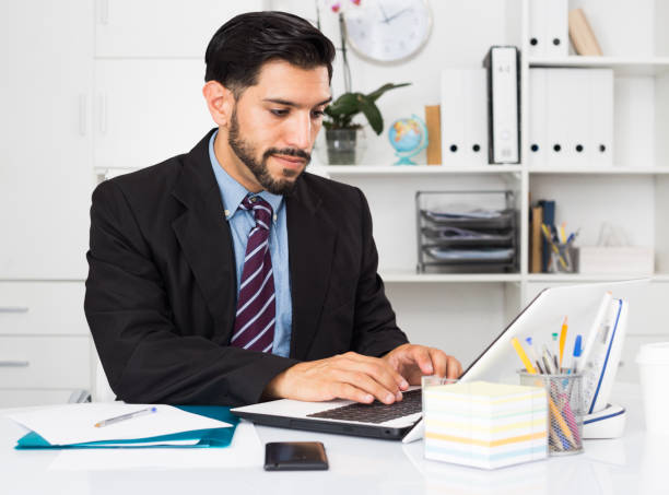 istock Smiling businessman is working behind laptop and reading documents 1143513532