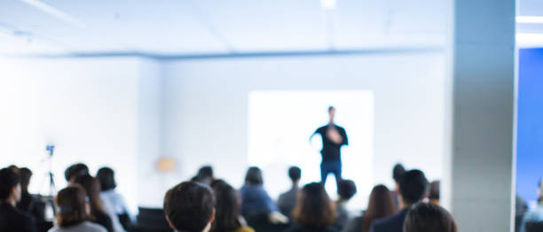 business conference photo. executive speaker on stage. business presentation presenter speech at tech entrepreneur meeting. corporate event audience. expert seminar lecture conference event. blurred. - seminar imagens e fotografias de stock