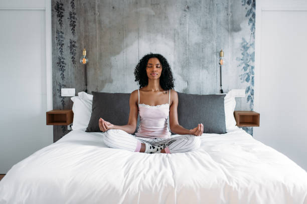 istock Attractive black woman on bed meditating 1143516611