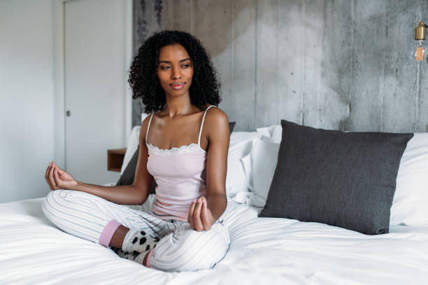 istock Attractive black woman on bed meditating 1143516617