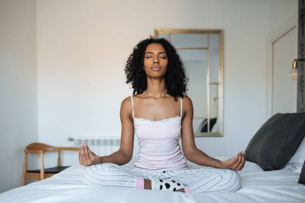 istock Attractive black woman on bed meditating 1143516618